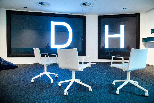 Three white chairs and two large screens bearing the letters DH